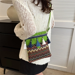 Detail of green bohemian crossbody bag with colorful fringes and woven wave patterns