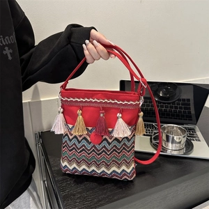 Detailed macro view of a red ethnic canvas bag with colorful tassels and woven textures