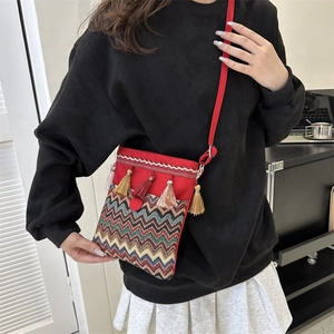 Detailed close-up of a red ethnic crossbody bag with bohemian embroidery and colorful tassels