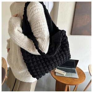 Detail of the bubble textured fabric and wide ruched shoulder strap on black tote bag