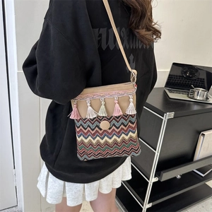 Close-up of bohemian crossbody bag with colorful wavy patterns and decorative tassels