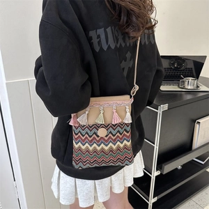Close-up of Bohemian knit crossbody bag with colorful tassels and wave pattern strap