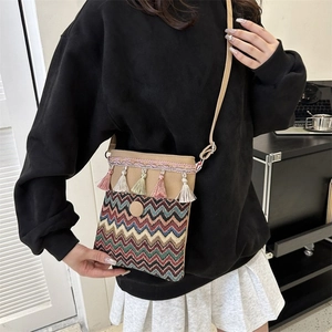 Detail of bohemian crossbody bag featuring colorful tassels and ethnic woven patterns