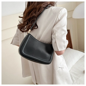 Detail of minimalist black matte leather underarm bag with gold adjustment buckle