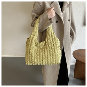 Detailed view of yellow popcorn textured tote bag with 3D bubble fabric on model arm