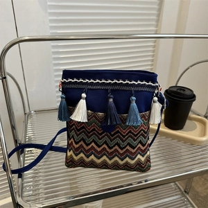 Detail of bohemian navy canvas crossbody bag featuring colorful wave weave and cotton tassels