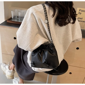 Détail du sac seau noir avec nœuds et bandoulière en chaîne argentée sur modèle