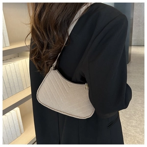 Close-up of beige quilted half-moon shoulder bag with V-shaped stitching on leather