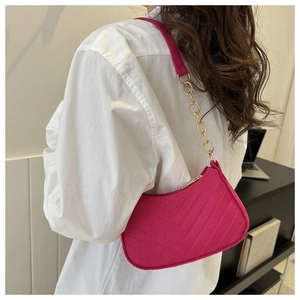 Detail of rose pink V-quilted faux suede baguette bag with gold chain shoulder strap
