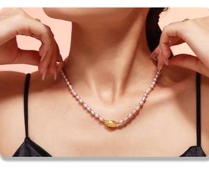 Close-up of French vintage freshwater pearl necklace with gold pendant on female model