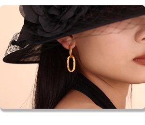 Detail of gold double oval twisted earrings with hammered texture on elegant model