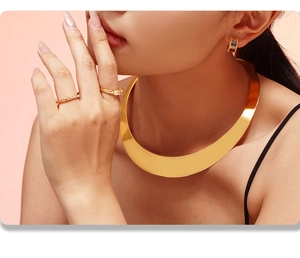 Gros plan d'un choker doré, de bagues en cristal et de boucles d'oreilles serties