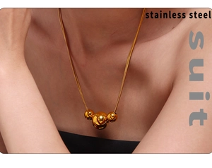 Close-up of double-layer stainless steel necklace with three polished golden beads