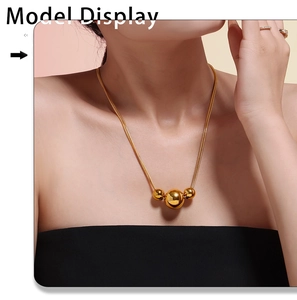 Model wearing gold triple-ball bead pendant on a sleek snake chain necklace