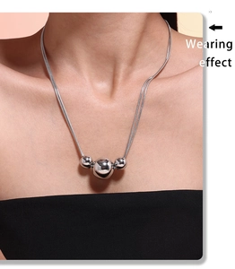 Close-up of polished silver geometric triple bead pendant on a sleek snake chain necklace