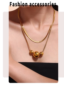 Detail of double-layered gold necklace with minimalist polished spheres on a sleek chain