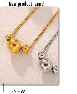Macro shot of minimalist gold and silver bead pendants on delicate steel chains