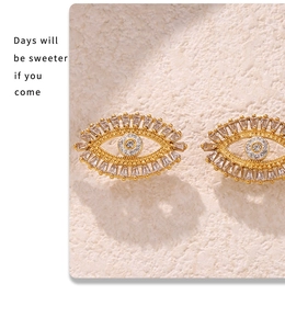 Close-up of gold-plated Evil Eye earrings with cubic zirconia stones on textured stone