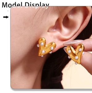 Detail of golden heart earrings with pearls worn by model to show size and texture