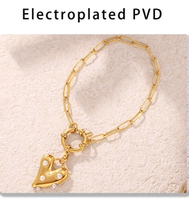 Detail of PVD gold heart pendant with pearl inlay on a paperclip chain necklace