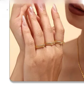 Close-up of three gold-plated stackable rings with micro-pave zircons and a round bead charm