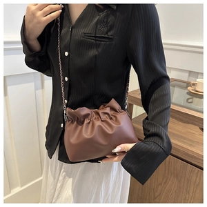 Detail of coffee brown ruched cloud bag with leather and chain strap on shoulder