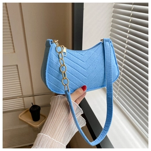Close-up of bright blue quilted felt shoulder bag with golden chain and V-pattern texture