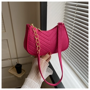 Close-up of fuchsia quilted shoulder bag with golden chain handle and fabric strap
