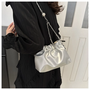 Detail of silver pleated bucket bag with metallic chain strap and round buckle ornament