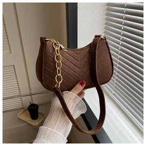 Detail of dark brown suede shoulder bag with V-shaped quilting and gold chain strap