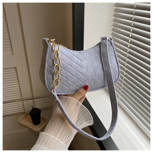 Detail of grey felt shoulder bag featuring V-shaped quilting and a gold chunky chain strap