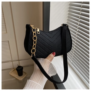Detail of black chevron quilted crescent bag with gold chain and woven shoulder strap