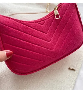 Close-up of fuchsia felt shoulder bag featuring dense V-shaped quilting and gold hardware