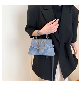 Detail of light blue crossbody bag with vintage golden buckle held by a model
