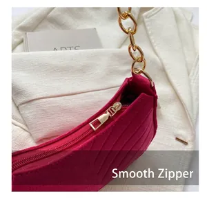 Detail shot of smooth metal zipper and magenta velvet fabric with gold chain strap