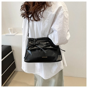 Fashionable black leather tote bag with pleated detail and bow shown on a model