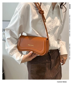Detail of a brown leather shoulder bag with gold logo and stylish knotted strap design