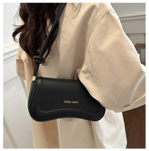 Detail of black leather underarm bag featuring knotted strap and gold Miss mini logo