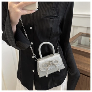 Detail of silver sequined mini handbag with crystal bow and metallic chain strap