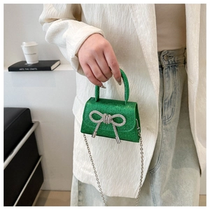 Close-up of grass green sequin mini bag with sparkling rhinestone double bow and chain
