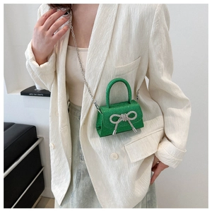 Detail of green sequin micro bag with silver rhinestone bow and metal chain strap