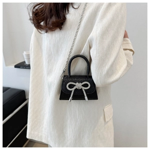 Détail d'un mini sac à main pailleté noir avec nœud argenté et bandoulière en chaîne