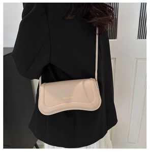 Close-up of a beige Miss Mini crossbody bag worn by a model in a black blazer