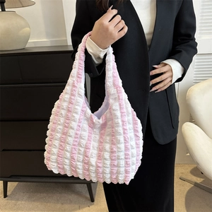 Striped pink and white bubble tote bag with pleated texture worn by a model in a modern room