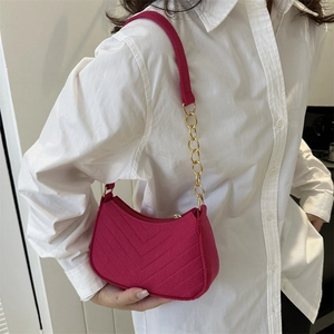 Fuchsia chevron quilted shoulder bag with gold chain strap worn by model in white shirt