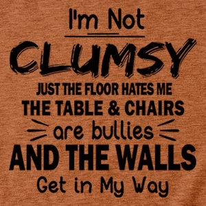 Close-up of 'I'M NOT CLUMSY' text print on a textured tan cotton fabric t-shirt