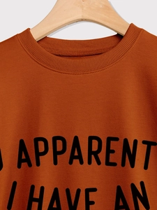 Detail of burnt orange crewneck sweatshirt with black letter print on wooden hanger