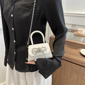 Mini white square crossbody bag with sparkling finish and rhinestone bow on model