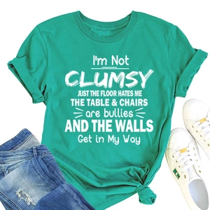 Green T-shirt with I'M NOT CLUMSY JUST slogan paired with jeans and sneakers