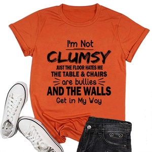 Close-up of bright orange crewneck T-shirt with black I'M NOT CLUMSY slogan print